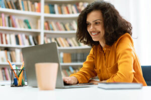 feliz-dama-de-raza-mixta-sentada-en-el-escritorio-usando-la-computadora-portC3A1til-y-viendo.jpg