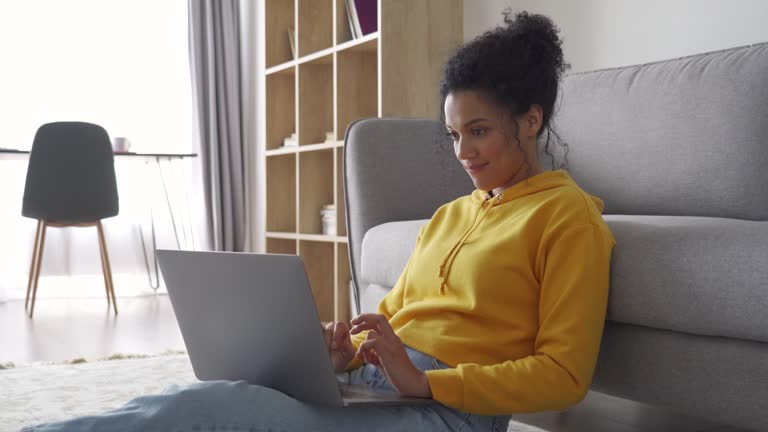 estudiante-afroamericana-sentada-en-el-suelo-de-su-casa-escribiendo-en-una-computadora.jpg