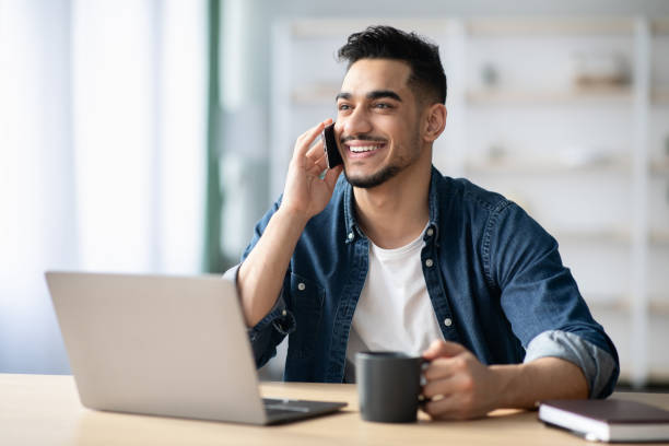 feliz-chico-C3A1rabe-freelancer-trabajando-desde-casa-teniendo-conversaciC3B3n-telefC3B3nica.jpg