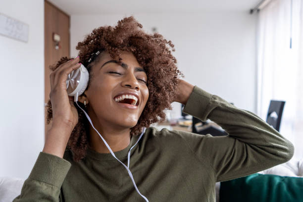 mujer-adulta-joven-con-cabello-afro-escuchando-mC3BAsica-con-auriculares-en-la-sala-de-estar-de.jpg
